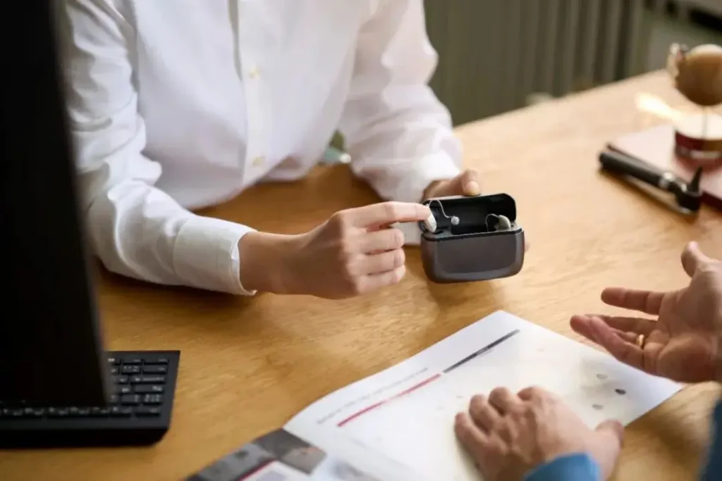 The audiologist holds the hearing aid